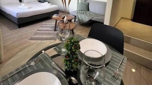 Une chambre moderne avec un lit, un canapé et un coin repas avec une table mise pour deux personnes.