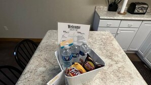 Una encimera de cocina con un cartel de bienvenida, botellas de agua y recipientes de aperitivos.