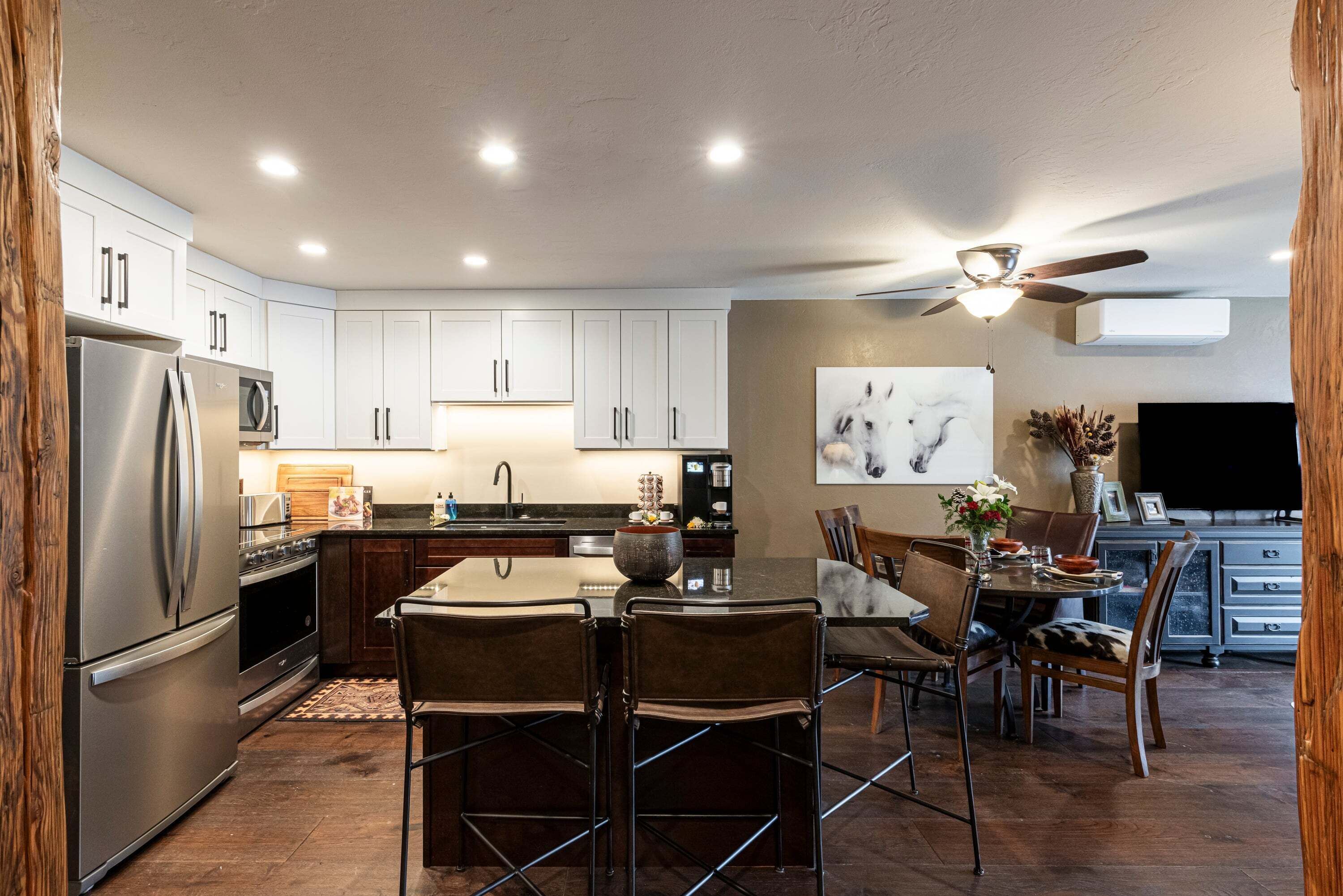 A modern kitchen with white cabinets, stainless steel appliances, and a dining area with a round table and chairs.