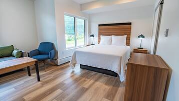 Une chambre à coucher moderne avec un grand lit, un bureau, une chaise et une table de chevet.