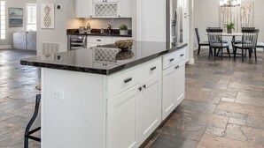 A spacious kitchen with white cabinetry, a granite countertop, and a central island.