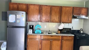 Eine Küche mit Holzschränken, einem Edelstahl-Kühlschrank, einer Kaffeemaschine, einem Toaster, einem Wasserkocher und einer Mikrowelle.