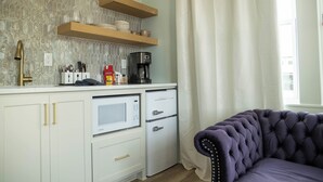 Eine kompakte Küche mit Mikrowelle, Kaffeemaschine und Stauraumschränken.