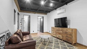 Una sala de estar moderna con un sofá de cuero, un mueble de madera y un televisor.