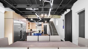 Una cocina moderna con electrodomésticos de acero inoxidable, una isla central y una escalera que sube a un nivel superior.