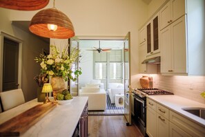 Eine moderne Küche mit weißen Schränken, einer Holz Arbeitsplatte und einem eingebauten Herd. Es gibt einen Essbereich mit einem weißen Tisch und Stühlen, und einen kleinen Teppich auf dem Boden.