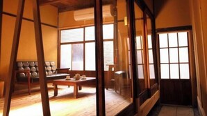 A traditional Japanese room with tatami flooring, a low table, cushions, and sliding doors. - Higashi Matsuyacho West (Kyoto)