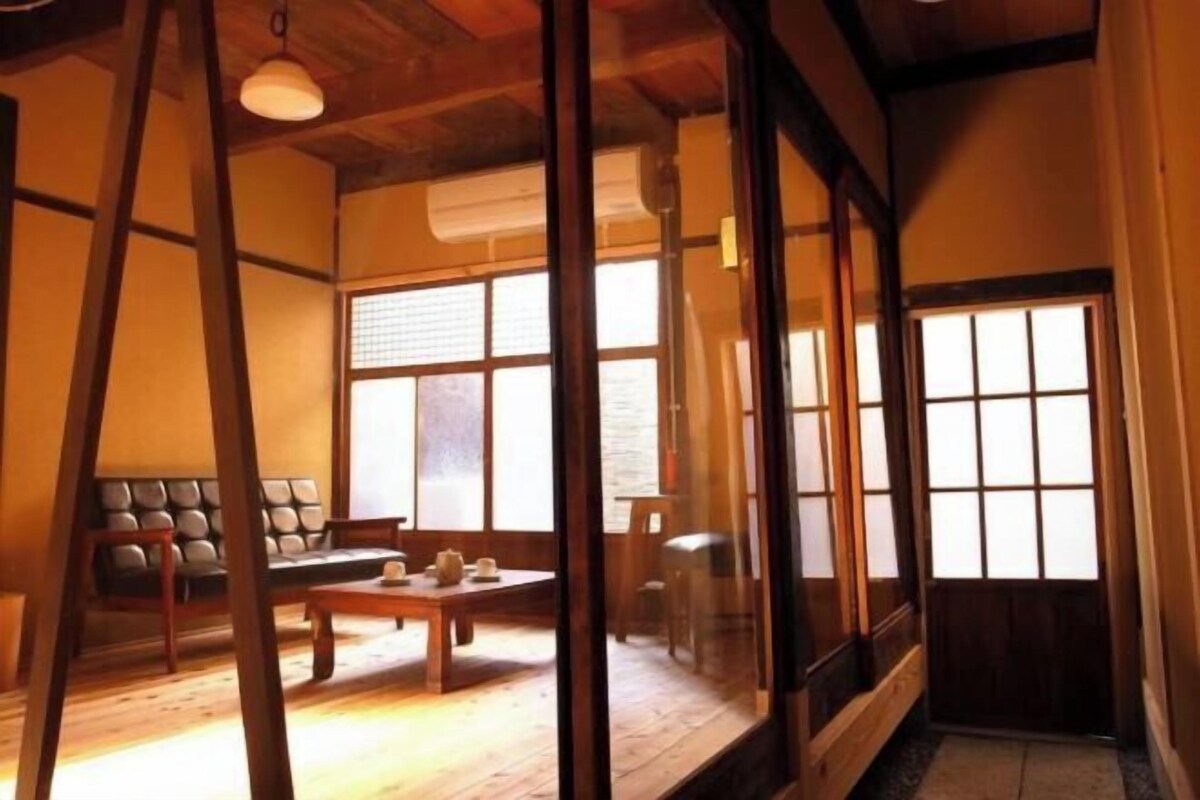 A traditional Japanese room with tatami flooring, a low table, cushions, and sliding doors.