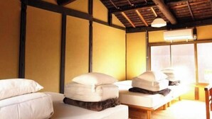 A room with two beds, wooden beams on the ceiling, and a window with blinds. - Higashi Matsuyacho West (Kyoto)