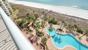 Ein Resort mit großem Schwimmbad, Palmen und Blick auf den Strand.