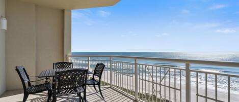 Enjoy the ocean view from this balcony with a table and chairs.