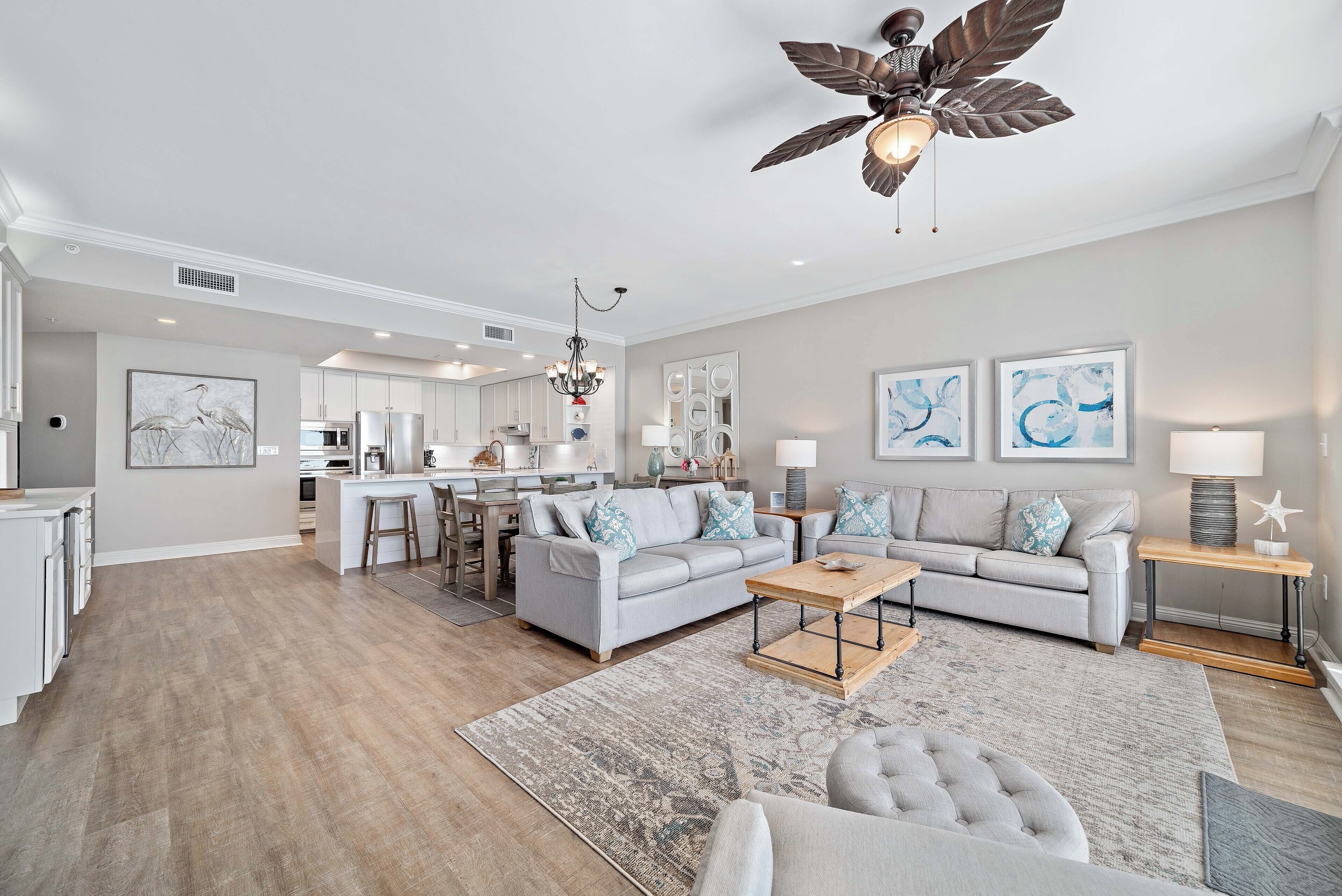 A spacious living room with a grey sofa, a coffee table, and a ceiling fan.