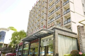 A multi-story hotel with a modern facade, large windows, and a covered entrance area. - Xinyu Holiday Hotel (Huangshan Tunxi) (Huangshan City)