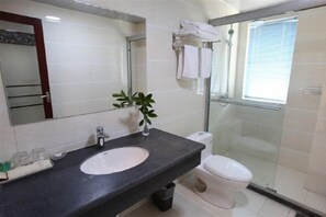 A modern bathroom with a black countertop sink, a mirror, a toilet, and a glass shower enclosure. - Xinyu Holiday Hotel (Huangshan Tunxi) (Huangshan City)