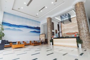 Un hall d’hôtel comprenant un comptoir d’accueil, un espace salon et une grande peinture murale.