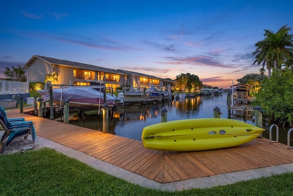 A waterfront hotel with a dock, kayaks, and boats.