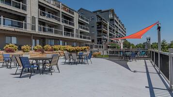 An outdoor patio with tables and chairs, surrounded by a fence and a red shade sail.