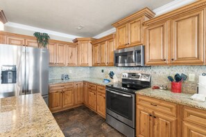 A kitchen with wooden cabinets, stainless steel appliances, granite countertops, and a tiled backsplash.