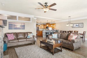 A spacious living room with two sofas, a coffee table, and a ceiling fan.