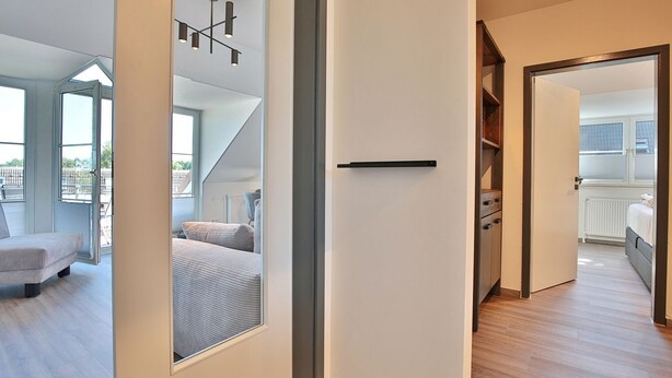 Een modern interieur met een trap naar een balkon, een bed met hoofdeinde en een gang met een deur.
