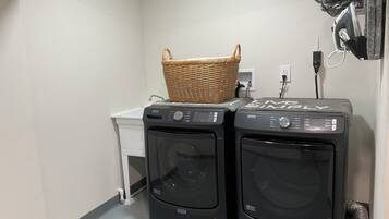 A laundry area with two Maytag front-loading washing machines, a small white laundry cart, and a wicker basket on top of the right machine.