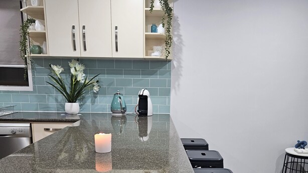 Una cocina moderna con encimera de granito, armarios blancos y salpicadero azul.