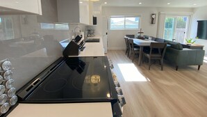 Una cocina moderna con una estufa negra, armarios blancos y un comedor con mesa y sillas.