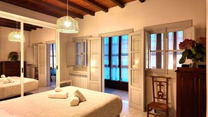 A hotel room with two beds, a wooden chair, a wooden cabinet, and a large mirror.