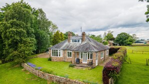A stone house with a well-maintained lawn and a stone wall.