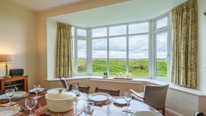 A dining room with a large bay window overlooking a green landscape.