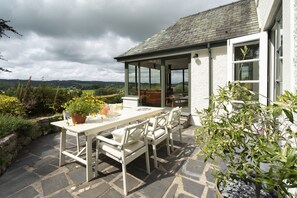 Enjoy al fresco dining in a tranquil setting surrounded by lush greenery and distant hills.