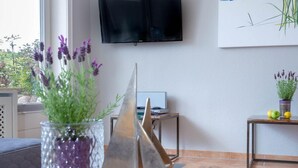 Una sala de estar moderna con una mesa de centro de vidrio, un modelo de velero y una planta de lavanda en maceta.