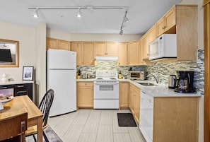 Compact kitchen with a stove, microwave, and coffee maker, perfect for preparing meals.