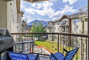 Enjoy a peaceful view of the surrounding neighborhood and mountains from this balcony, complete with a grill and comfortable seating.