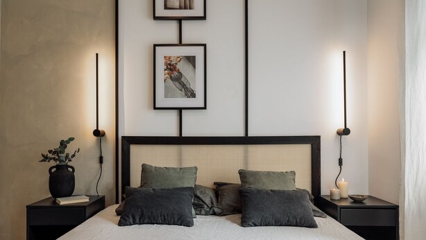 A modern bedroom with a large bed, two bedside tables, a wall-mounted light fixture, and a framed picture above the bed. - Holzer - 2 bedrooms in Sant Antoni (Barcelona)