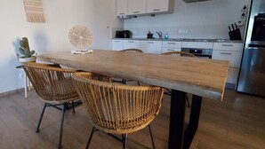 Une cuisine moderne avec une table à manger en bois, des chaises en osier et un luminaire suspendu.