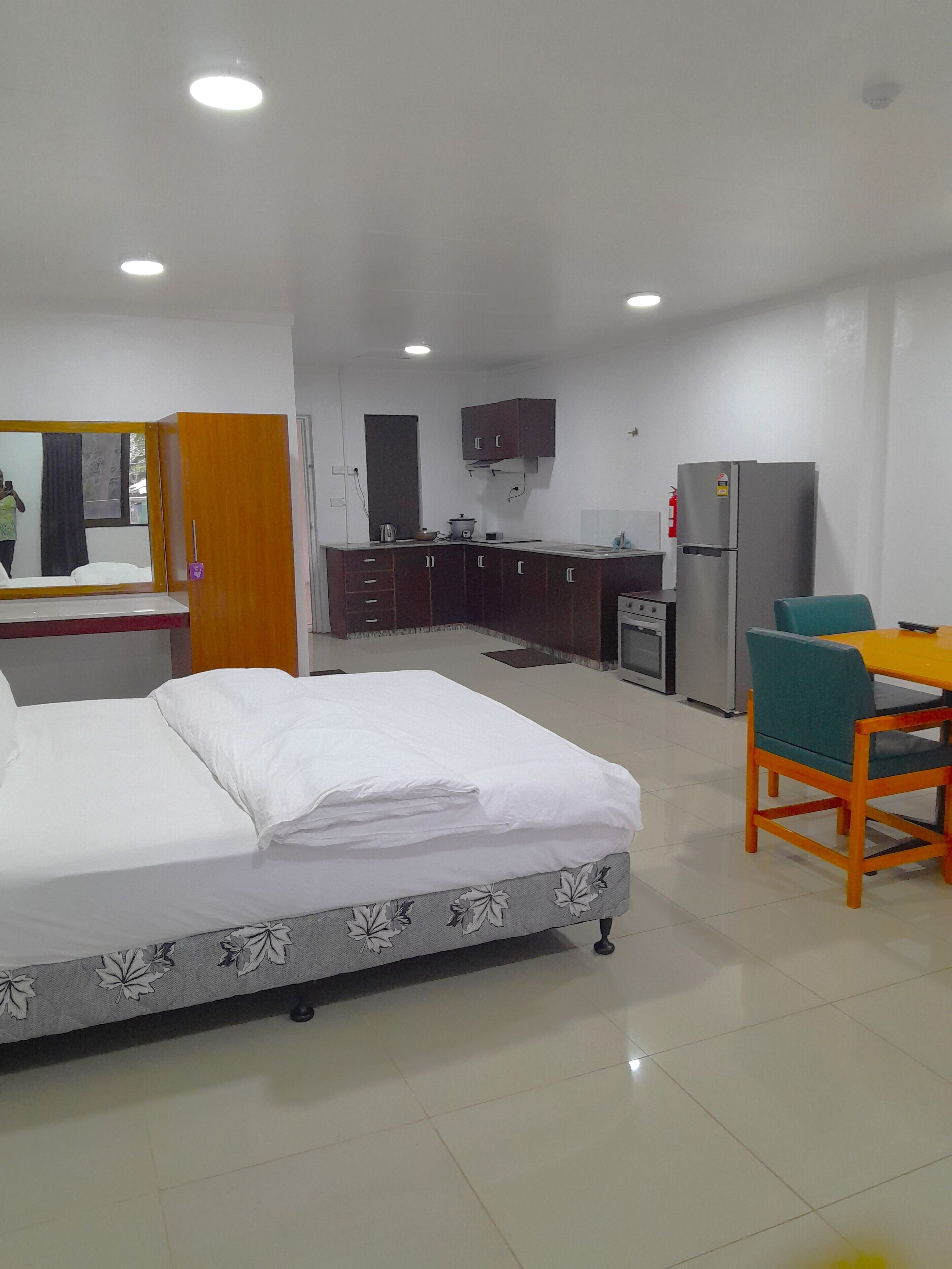 Une chambre d’hôtel comprenant un lit, une petite kitchenette, une table à manger avec des chaises et un miroir.