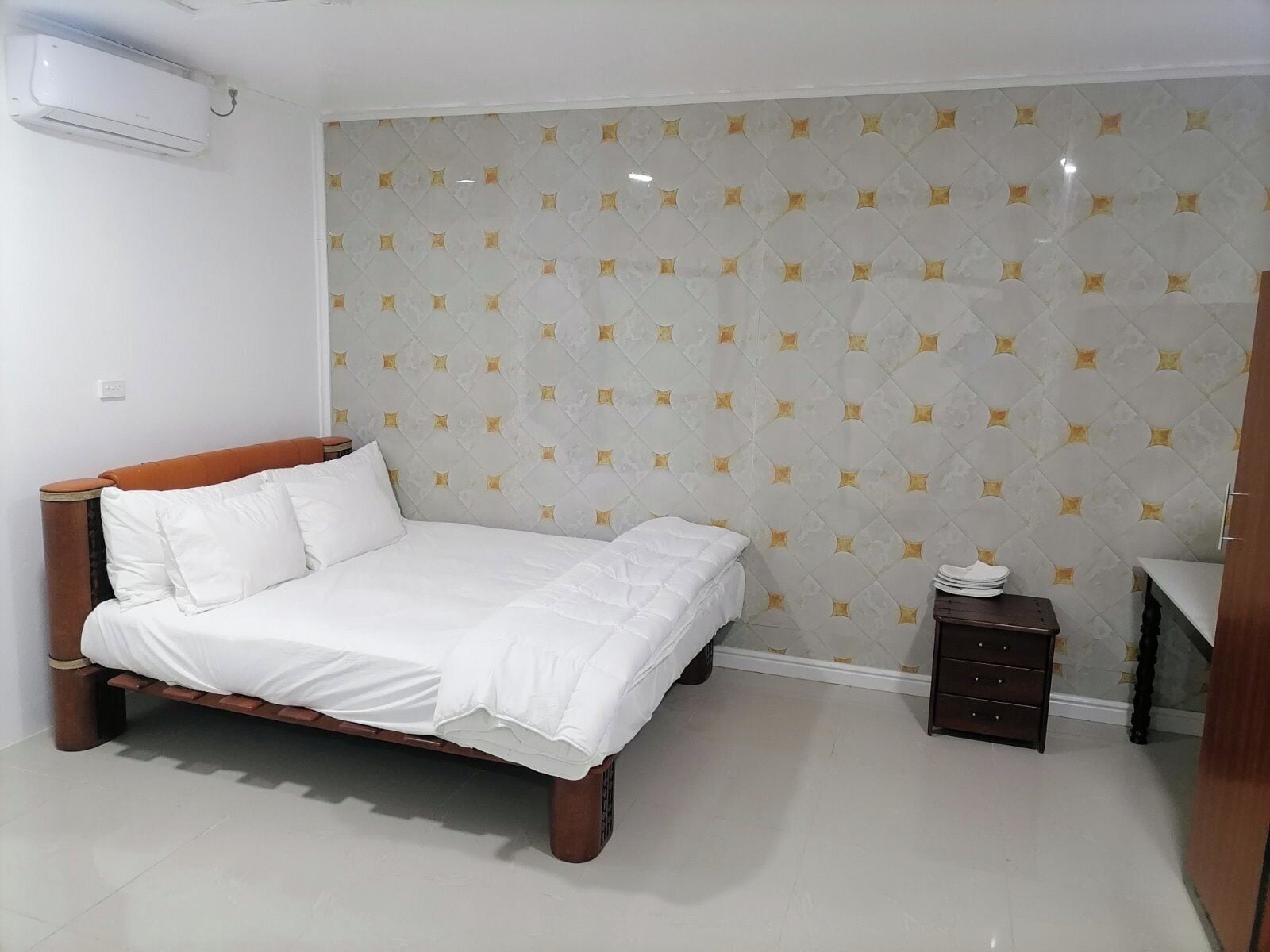 Ein Schlafzimmer mit einem Bett, einem Nachttisch und einer Wand-Klimaanlage.