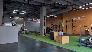 A gym with various exercise equipment, a green artificial turf floor, and a brick wall with the text "MOVE HUMAN PERFORMANCE". - Rosa Negra | Cozy Suite at Stadio (Medellín)