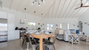 Una cocina amplia con comedor, muebles blancos y un ventilador de techo.