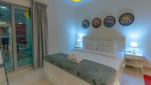Et hotelværelse med seng, to sengeborde med lamper, et vindue med gardiner og udsigt over byen.