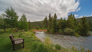 A bench by a river with a wooden bridge in the background. - Snowdance B102 (Keystone)