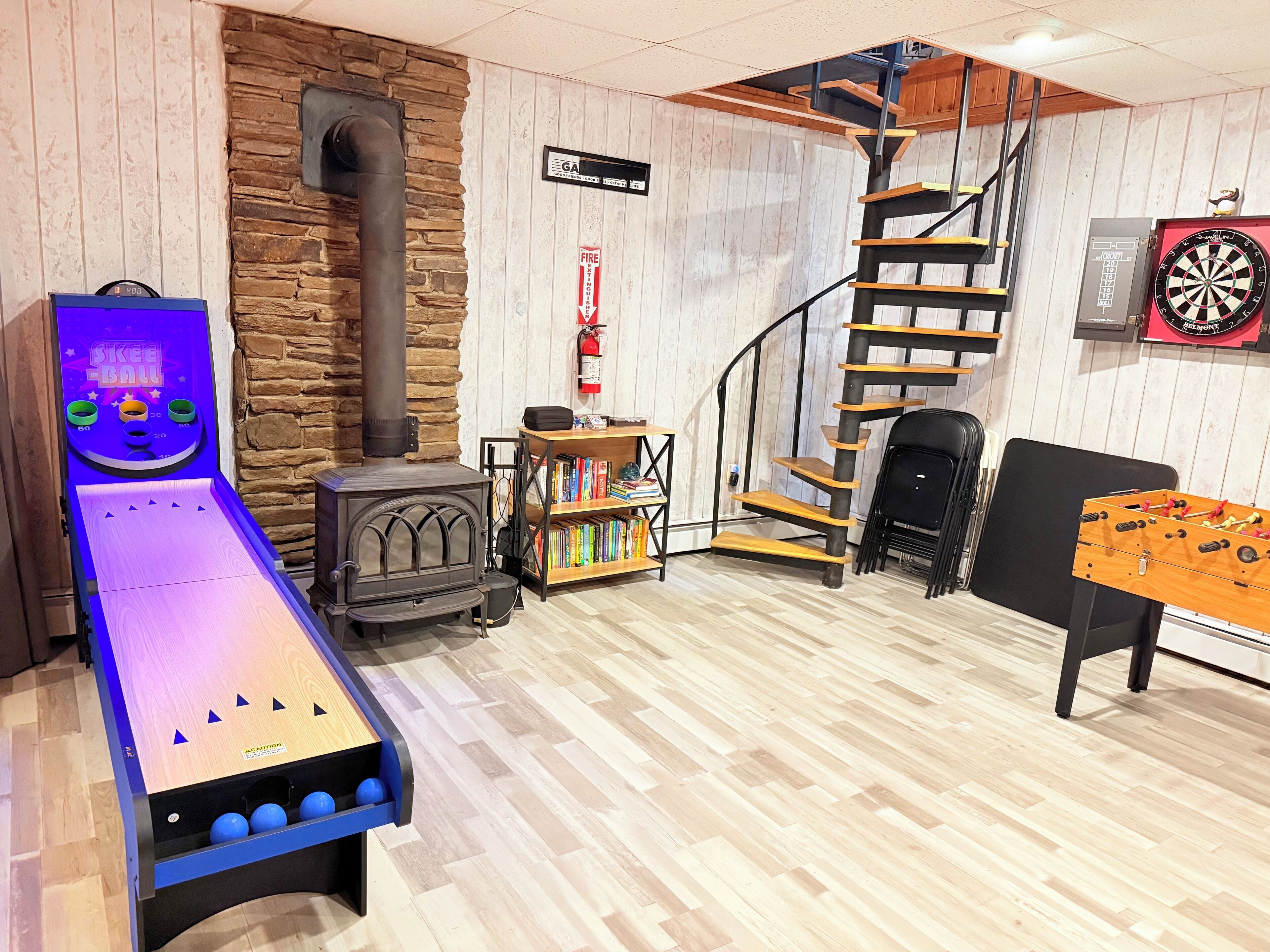 Une pièce équipée d’un baby-foot, d’un jeu de fléchettes, d’une bibliothèque, d’une cheminée et d’un escalier en colimaçon.