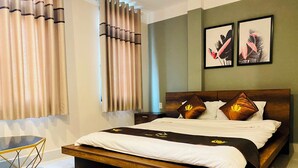 A hotel room with a large bed, a wooden headboard, a nightstand, and two framed pictures on the wall. - Trieu Nguyen Hotel (Ho Chi Minh City)