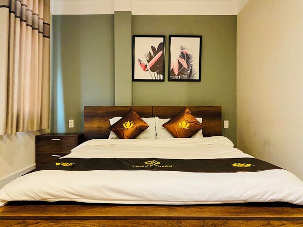 A neatly made bed with a black and white bedspread, two pillows with a lotus design, and two framed pictures on the wall above. - Trieu Nguyen Hotel (Ho Chi Minh City)