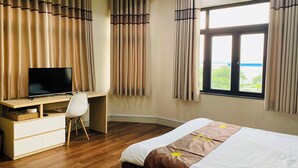 A hotel room with a bed, a desk with a TV, and curtains. - Trieu Nguyen Hotel (Ho Chi Minh City)