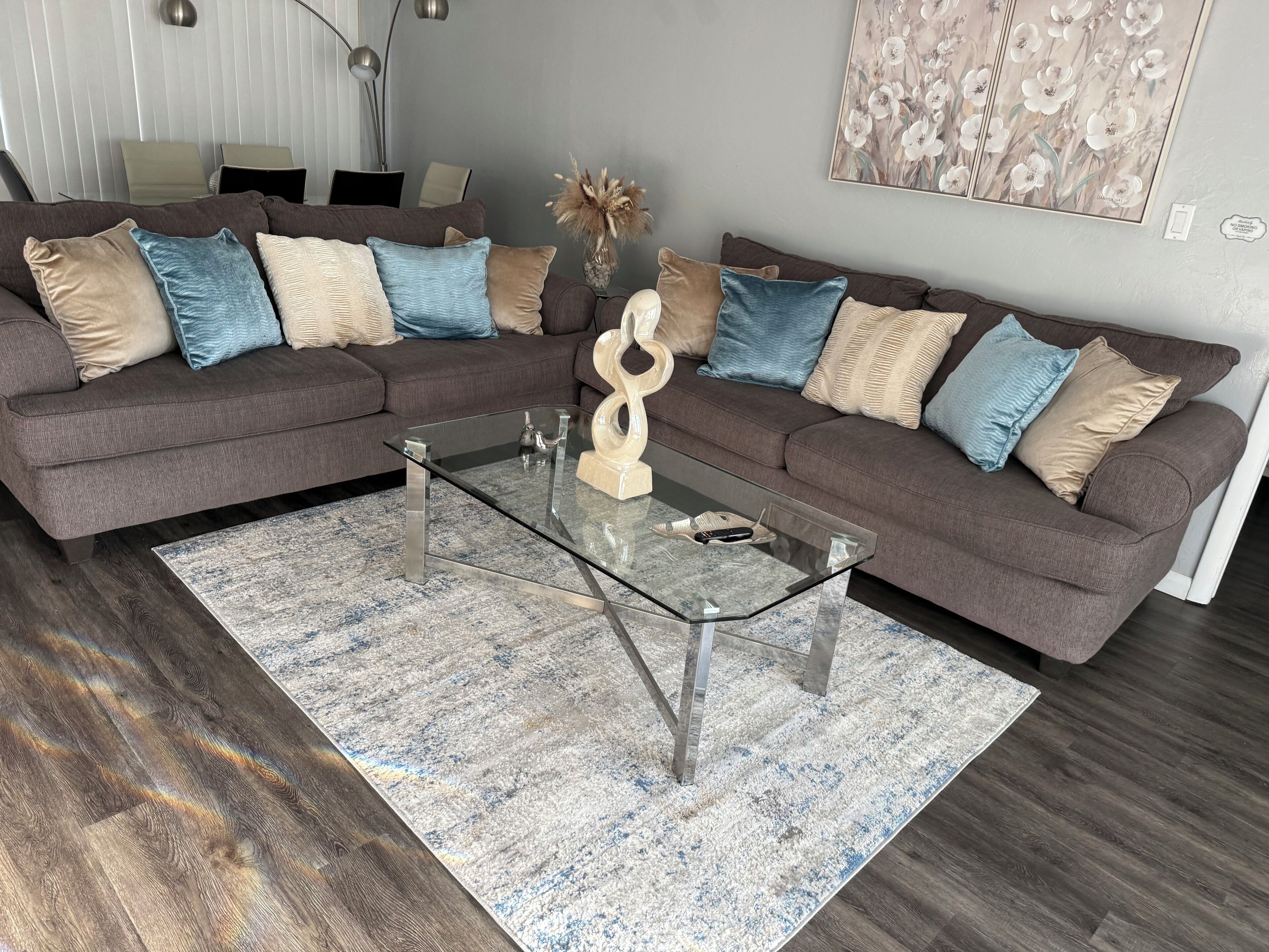 Een moderne woonkamer met een modulaire bank, een glazen salontafel en een kamerkleed met een patroon.