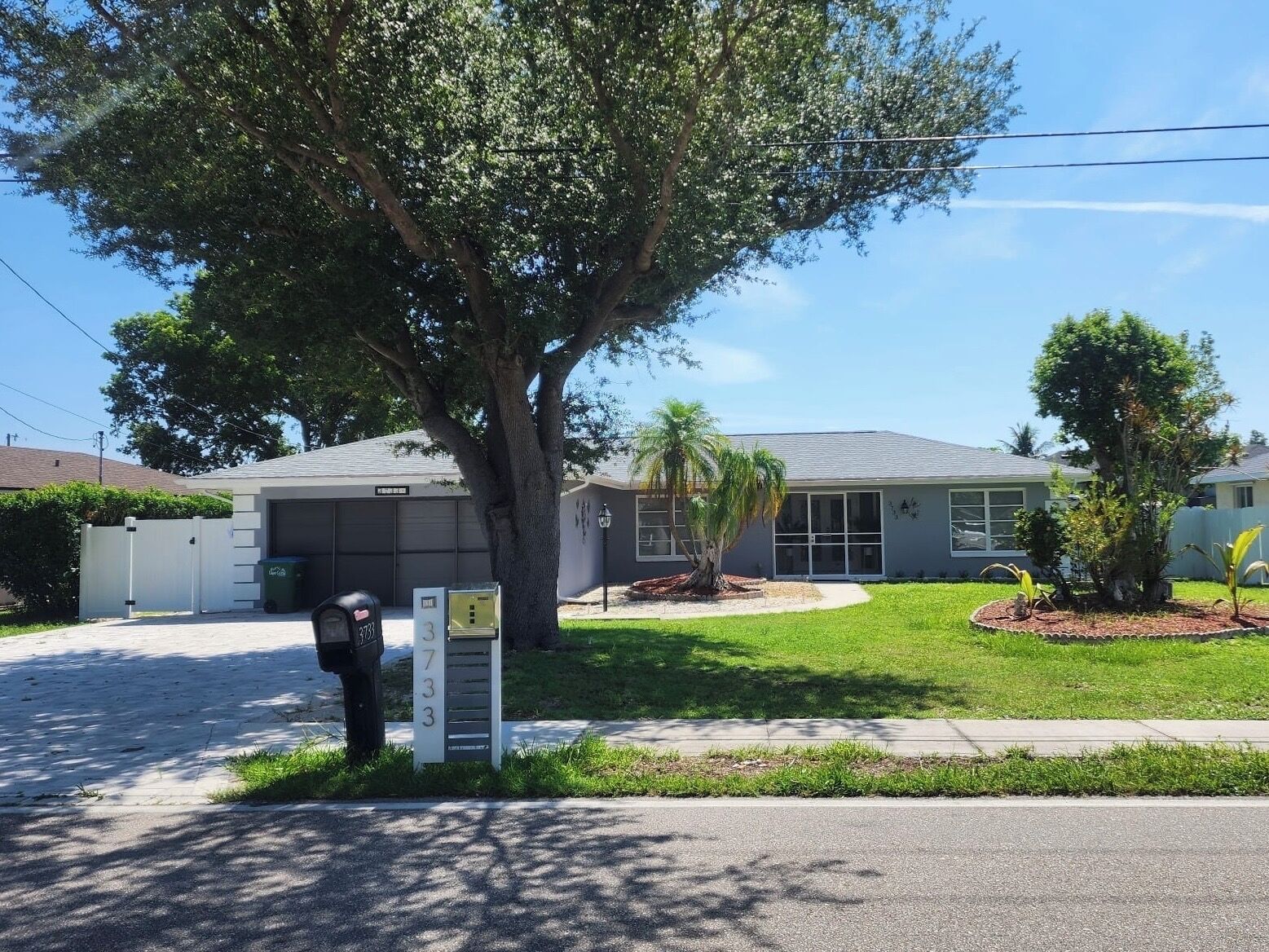 A residential property with a garage, a large tree, and a well-maintained lawn.