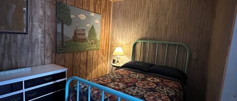 A bedroom with a bed, a nightstand, a dresser, a ceiling fan, and a wall-mounted painting.
