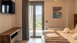 Una habitación de hotel moderna con una cama grande, un televisor de pantalla plana, un cuadro y vistas al campo.